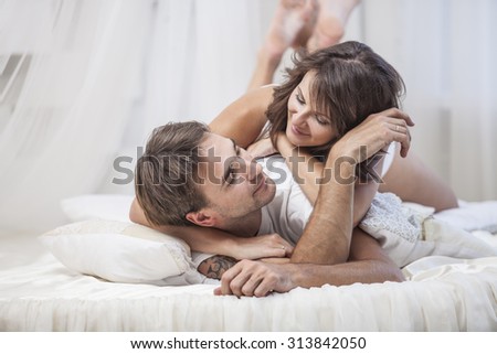 Couple man and woman lay cuddling on the bed at home. Love, family, relationships