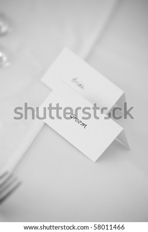 Bride and Grom place cards. Wedding table with white cloth and cutrely.