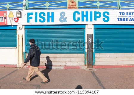 BRIGHTON, UK - FEBRUARY 8, 2011: Man walking in front of closed fish and chips shop on February 8, 2011 in Brighton, UK. Stores are closed over the winter there are few tourists.