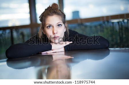 Beautiful woman looking intensely with chin on hands with slight reflection on table
