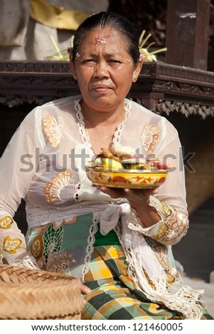 BALI - FEBRUARY 1. Priest\'s wife with fruit offering in temple for Galungan ceremony on February 1, 2012 in Bali, Indonesia. Galungan\'s a Balinese holiday occuring every 210 days lasting 10 days.