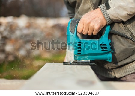 Carpenter cutting wood en with an electric jigsaw