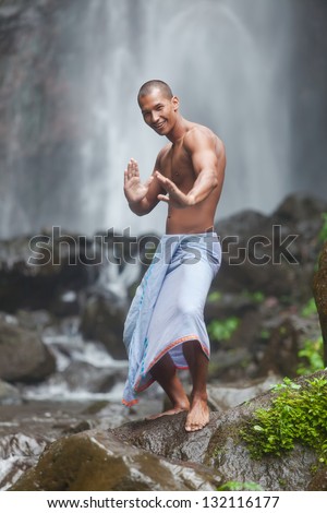 Young handsome man enjoying waterfall in the tropics