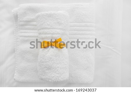 White towels with yellow ribbon folded on white sheets.