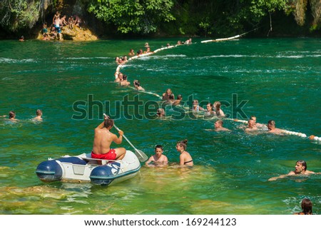 KRKA NATIONAL PARK, CROATIA - JUL 28: Tourists swimming in a river and boat paddling on July 28, 2012 on Krka National Park, Croatia. One of most famous Croatian tourist attraction.