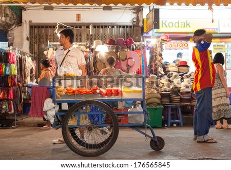 BANGKOK, THAILAND - JANUARY 9, 2012: Local man stands behind his street food cart on Khao San Road. Everyday thousands of tourists and locals buys food on these carts and stalls.