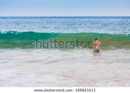 HIKKADUWA, SRI LANKA - FEBRUARY 20, 2014: Older man entering the sea at Hikkaduwa beach well known tourist international destination for board surfing.