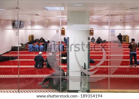 DOHA, QATAR - FEBRUARY 18, 2014: Muslim men praying in one of 13 prayer rooms at Doha International Airport, the only commercial airport in Qatar.