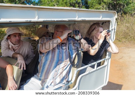 YALA NATIONAL PARK, SRI LANKA - MARCH 4, 2014: Tourists looking through binoculars during safari tour in the Yala park. Yala is the second largest national park in Sri Lanka.