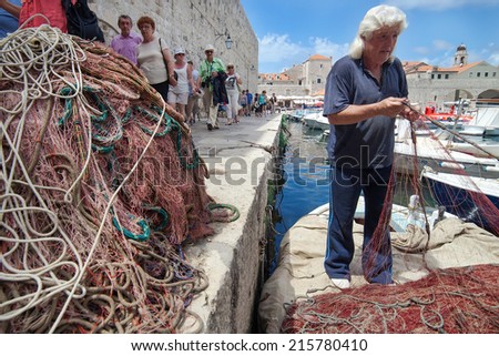 DUBROVNIK, CROATIA - MAY 26, 2014: Local fisherman in city port holding fishing net. Thanks to local fishermen Dubrovnik is brimming with fresh seafood.
