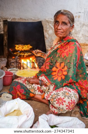 KAMALAPURAM, INDIA - 02 FEBRUARY 2015: Elderly Indian woman in traditional clothes frying vegatables on a market close to Hampi
