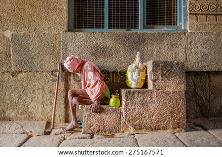 HAMPI, INDIA - 28 JANUARY 2015: Elderly Indian man begging in Virupaksha Temple which is part of Group of Monuments at Hampi, designated a UNESCO World Heritage Site.