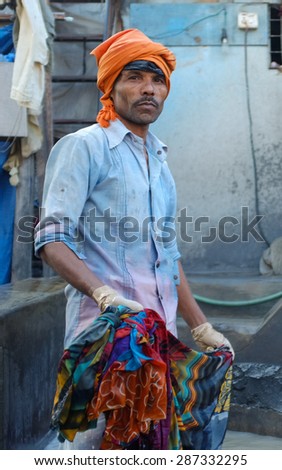 MUMBAI, INDIA - 10 JANUARY 2015: Indian worker washing a sari in Dhobi ghat.