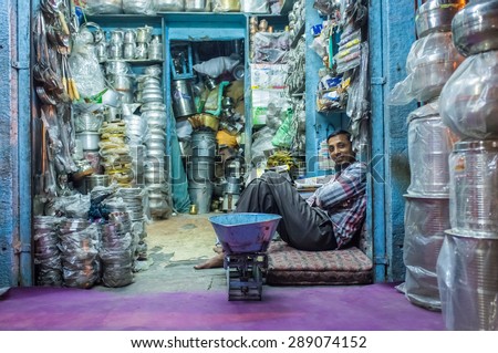 JODHPUR, INDIA - 10 FEBRUARY 2015: Worker sits and rests before closing time. Stores with kitchen pottery and other products made from metal are common on Asian markets.