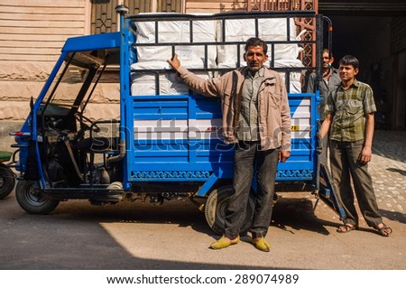 JODHPUR, INDIA - 10 FEBRUARY 2015: Men stand next to delivery three-wheeler with cargo in the back.