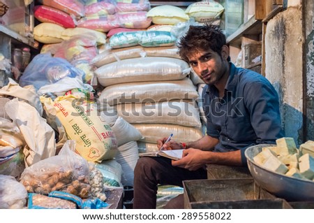 JODHPUR, INDIA - 10 FEBRUARY 2015: Young India man sits in store and writes down days income in notebook. Late working hours are common in India\'s markets.