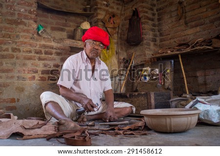 GODWAR REGION, INDIA - 13 FEBRUARY 2015: Elderly Indian shoemaker from Rabari tribe makes new pair of traditional shoes in workshop. Rabari or Rewari are an Indian community in the state of Gujarat.