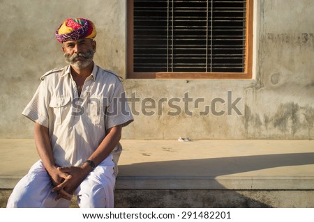 GODWAR REGION, INDIA - 14 FEBRUARY 2015: Adult Indian man with colorful turban and curled mustache sits in street.