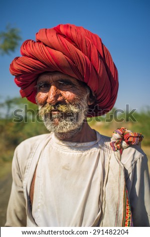 GODWAR REGION, INDIA - 14 FEBRUARY 2015: Elderly Rabari tribesman with big red turban stands on road. Rabari or Rewari are an Indian community in the state of Gujarat.