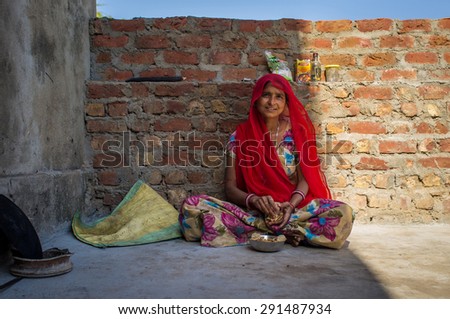 GODWAR REGION, INDIA - 13 FEBRUARY 2015: Indian woman in sari sits and eats chapati for breakfast.