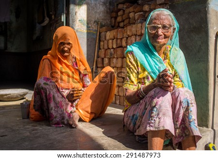 GODWAR REGION, INDIA - 13 FEBRUARY 2015: Two elderly Indian woman in sari\'s with covered heads sit in doorway of home.
