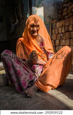 GODWAR REGION, INDIA - 13 FEBRUARY 2015: Elderly Indian woman in sari with covered head sits in doorway of home.