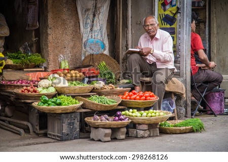 MUMBAI, INDIA - 17 JANUARY 2015: Elderly Indian businessman waits for customers in front of grocery store in market street.