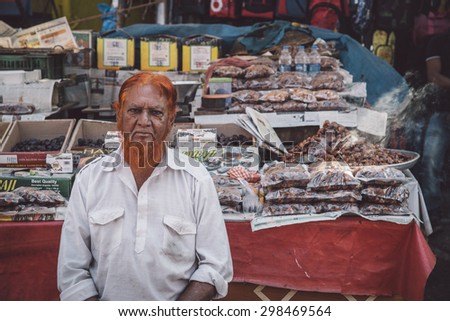 MUMBAI, INDIA - 11 JANUARY 2015: Indian street vendor with orange hennaed beard sits next to street stall. Post-processed with grain, texture and colour effect.