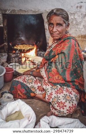 KAMALAPURAM, INDIA - 02 FABRUARY 2015: Elderly Indian woman in traditional clothes fries vegatables. Post-processed with grain, texture and colour effect.