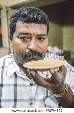 MUMBAI, INDIA - 05 FEBRUARY 2015: Portrait of Indian man drinks milk tea in traditional style. Post-processed with grain, texture and colour effect.