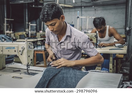 MUMBAI, INDIA - 12 JANUARY 2015: Indian workers sew in clothing factory in Dharavi slum. Post-processed with grain, texture and colour effect.