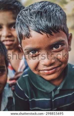 HAMPI, INDIA - 31 JANUARY 2015: Indian boy with friends in background. Post-processed with grain, texture and colour effect.