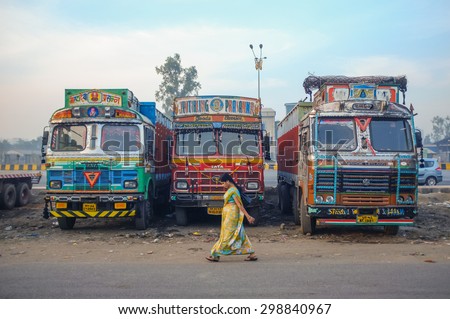 MUMBAI, INDIA - 05 FEBRUARY 2015: Woman walking by parked trucks on highway rest area decorated in traditional Indian style.