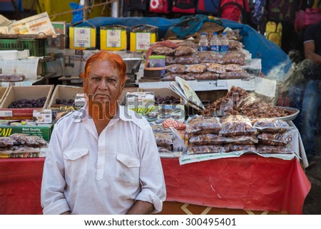 MUMBAI, INDIA - 11 JANUARY 2015: Indian street vendor with orange hennaed beard sits next to street stall. Muslim men dye there beards in the months of Ramadan or after pilgrimage to Mecca.