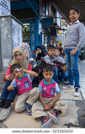 PIRAEUS, GREECE: SEPTEMBER 19, 2015: Family of immigrants and refugees from Middle East and North Africa sitting at the cardboard box at street.
