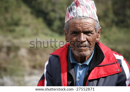 ANNAPURNA, NEPAL - APRIL 5: Old Nepali man with traditional hat rests on steep trail in Annapurna, Nepal April 5, 2008. Annapurna trail is well known for its trekking activities.