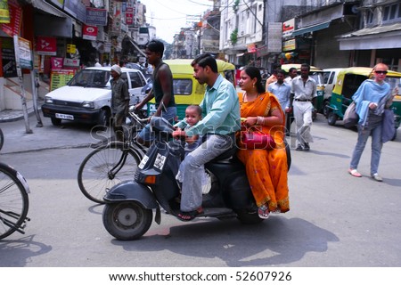 DELHI - SEPTEMBER 19: Mother, father and small child riding on scooter through busy city street on September 19, 2007 in Delhi, India. Up to six family members manage to ride these  two wheelers.