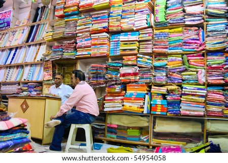 DELHI - DECEMBER 2: Two textile merchants sit in a wholesale shop stacked with fabric on shelves on December 2, 2007 in Delhi, India. Textiles exports may touch $24 billion in 2010-11