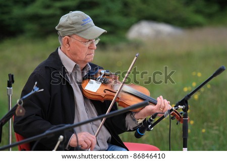 ROCKY HARBOUR, CANADA – JULY 16: A man plays violin on July 16, 2011 in Rocky Harbour, Newfoundland. The outdoor party was part of Parks Canada’s 100th anniversary.