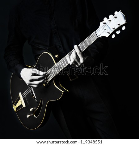 Guitar electric Guitarist playing black music instrument in hands closeup on black
