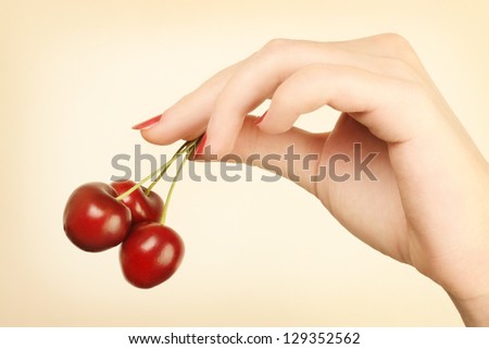 Hand with cherry. Ripe cherries in the woman\'s hand with red nails