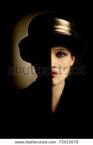 Woman face with black half. Artistic portrait of beautiful woman in black hat
