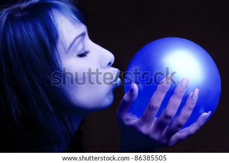 Artistic portrait of woman blue profile kissing balloon in the hand on black