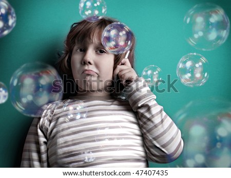 little boy talking on mobile phone while around him flying balloons