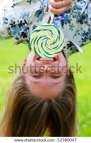 Upside-down girl eating big green candy