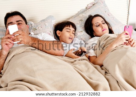 Family with mobile phone in the bed