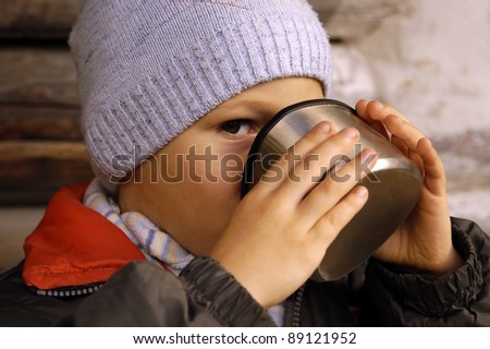 Child drinks from thermos cup, chilly weather