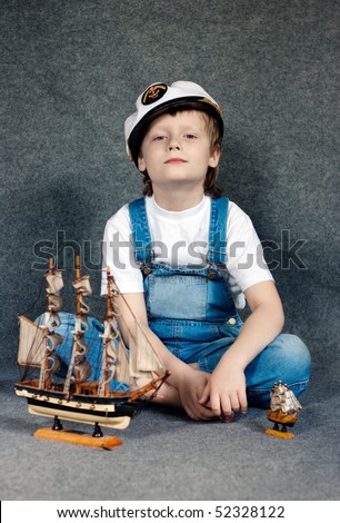 Portrait of the cute dreaming child with the model ship.