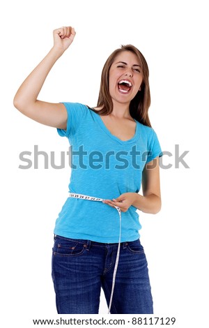 pretty young woman rejoicing over weight loss success. One hand holds a tape measure, the other is raised in triumph as she shouts for joy at her accomplishment