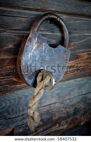 The old lock and key against a wooden wall